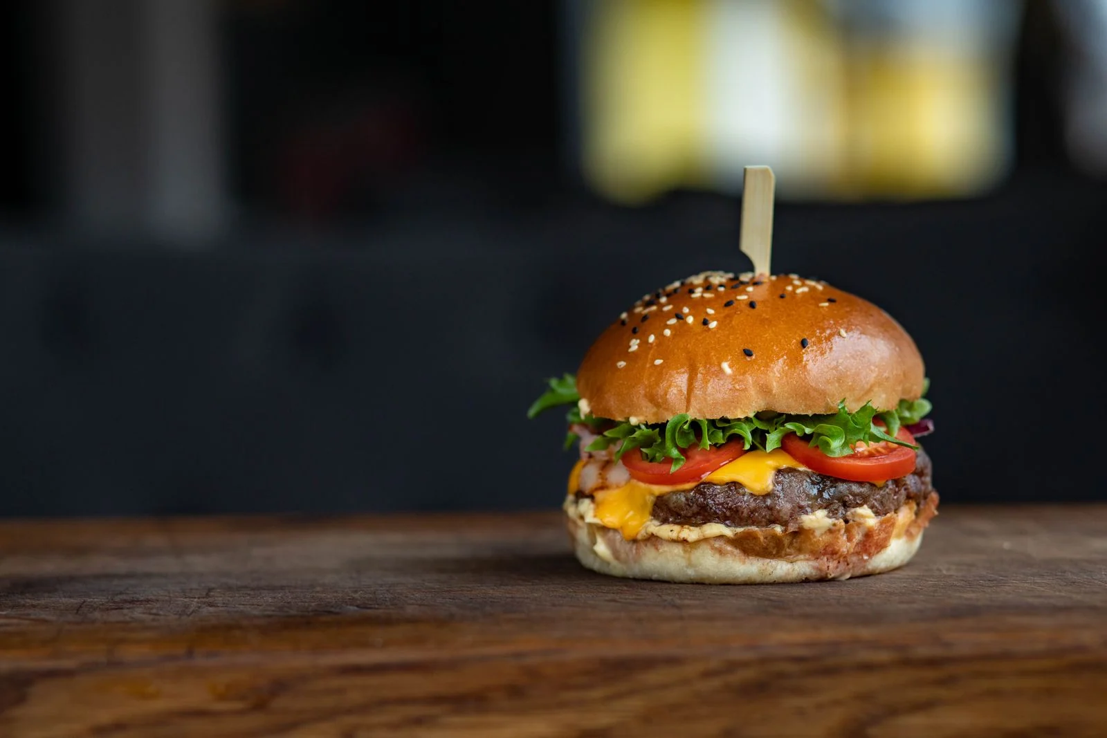 Cheeseburger with lettuce and tomato on a wooden board